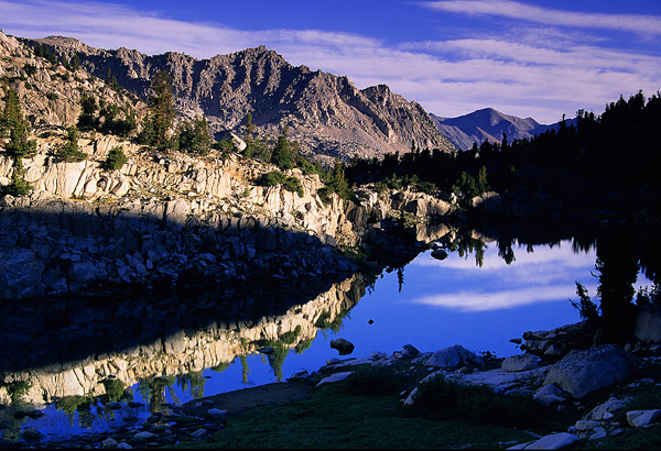 Morning shadows creeping across mountains and a lake in Sixty Lakes Basin in the High Sierra