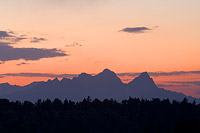 Telephoto image of mountains at twilight with a red and pink sky and the mountains black in silhouette