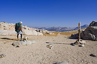 Backpacker standing on the trail on Goodale Pass with an amazing view north into the Sierra Nevada Mountains