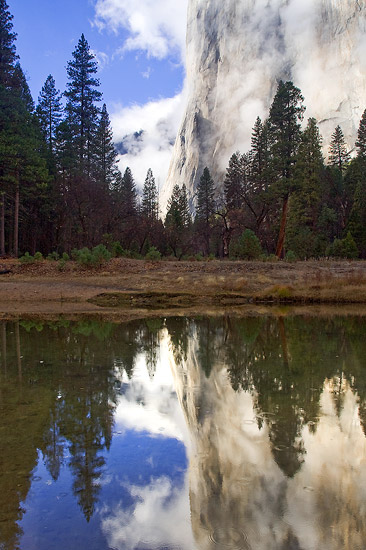 Reflection of the lower half of El Capitan in the Merced River with clouds breaking after a fall storm