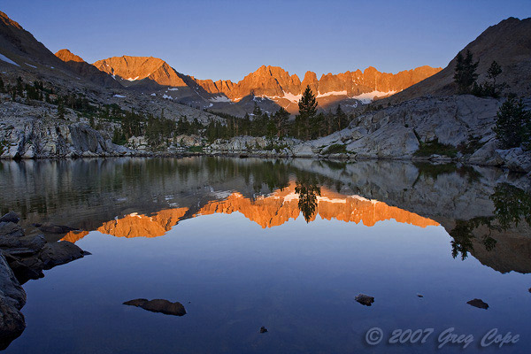 Sunrise alpenglow off the dramatic kaweah peaks reflected in a placid lake
